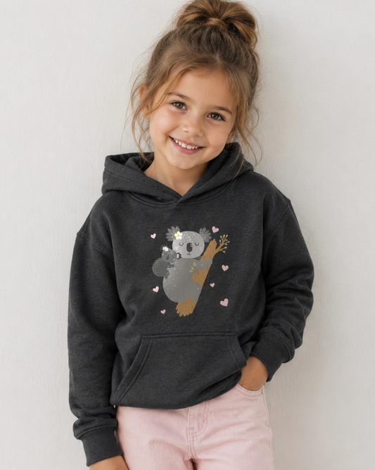 Girl modelling a charcoal grey kids koala hoodie with pink heart design and light pink jeans in a studio photo