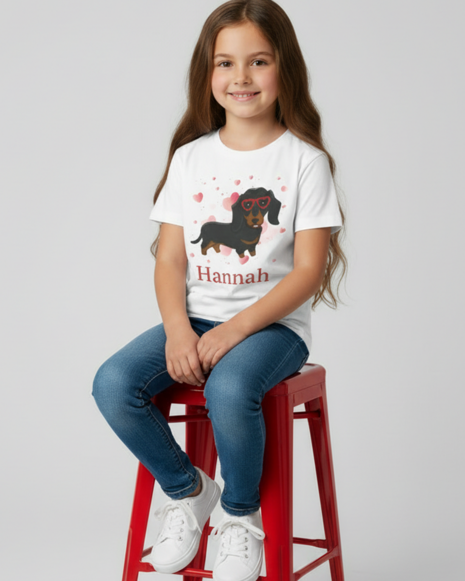 Girl sitting on red stool wearing a personalised dachshund hearts t-shirt with custom name