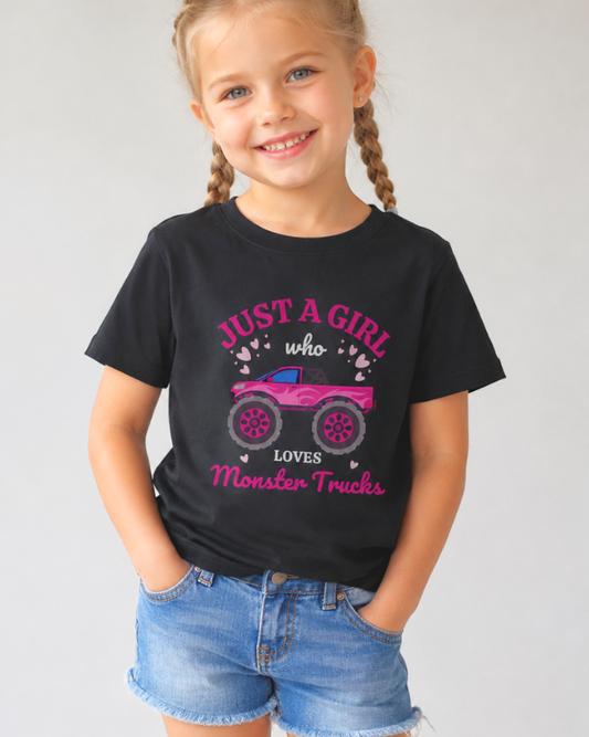 Young girl wearing a black t-shirt with a graphic of a pink monster truck -studio setting.