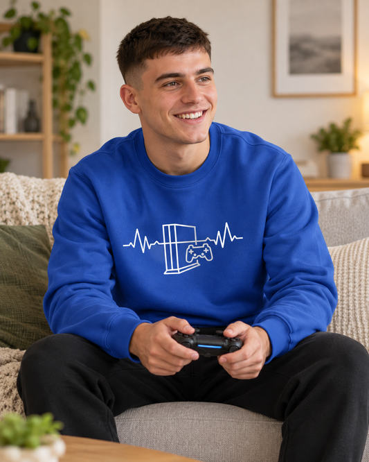 Young man wearing a royal blue gaming heartbeat sweatshirt and black joggers while playing video games on a sofa.