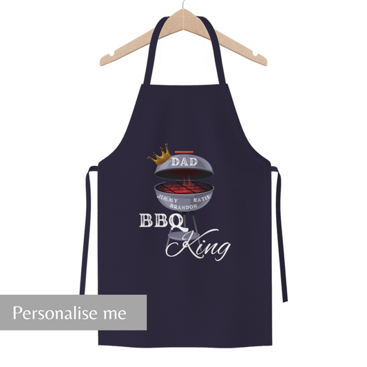 A navy blue apron with 'BBQ KING' text and a graphic of a grill, displayed on a hanger.
