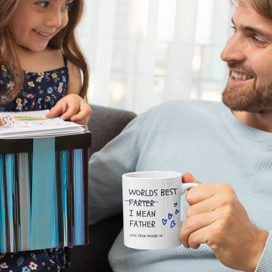 A man and a child smiling, with the man holding a white mug that says 'WORLD'S BEST FARTER.
